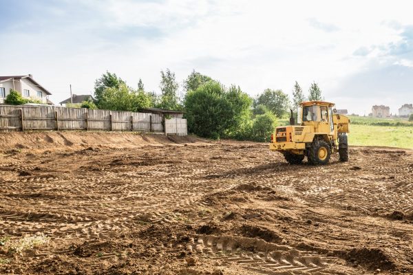 large yellow wheel loader aligns a piece of land for a new building